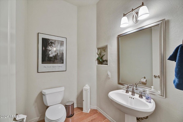 bathroom with wood-type flooring, toilet, and sink