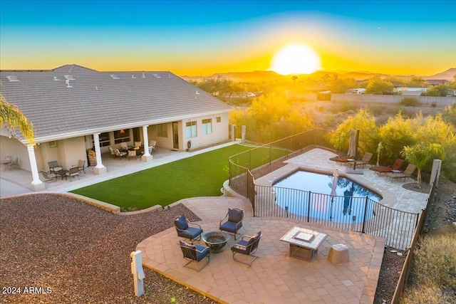 pool at dusk with a patio and a fire pit