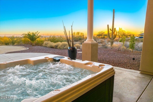 patio terrace at dusk featuring a hot tub