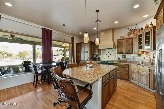 kitchen with sink, a center island, light hardwood / wood-style flooring, and custom exhaust hood