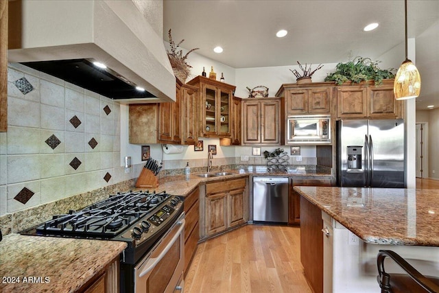 kitchen featuring light stone countertops, sink, stainless steel appliances, and range hood