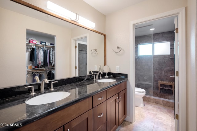 bathroom with tiled shower, tile patterned flooring, vanity, and toilet