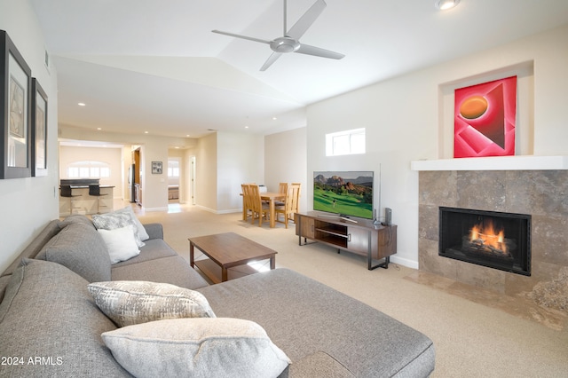 carpeted living room featuring a tiled fireplace, lofted ceiling, and ceiling fan