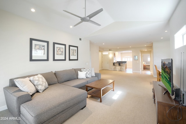 carpeted living room with ceiling fan and vaulted ceiling