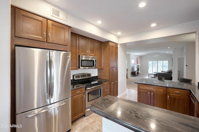 kitchen featuring stainless steel appliances, light tile patterned flooring, and vaulted ceiling