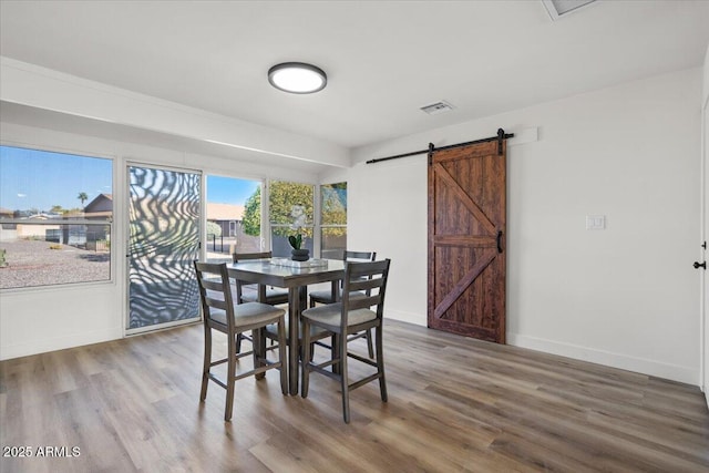 dining room with hardwood / wood-style flooring and a barn door