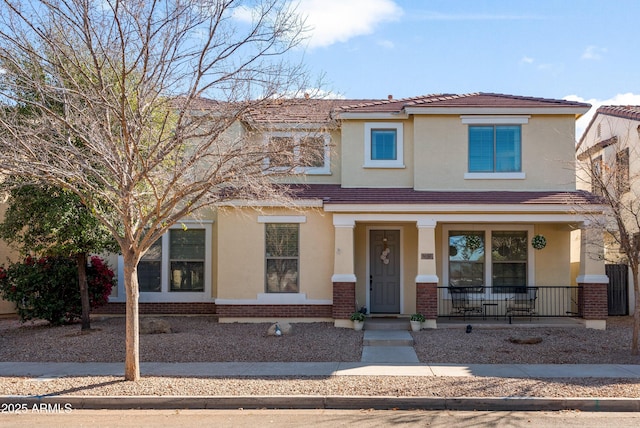 view of front of property with a porch, brick siding, and stucco siding