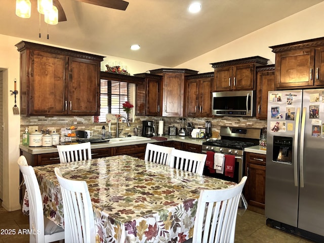 kitchen with backsplash, sink, vaulted ceiling, and appliances with stainless steel finishes