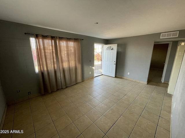 empty room featuring visible vents, baseboards, and light tile patterned floors