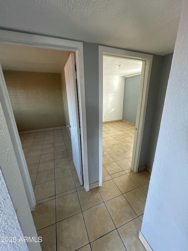 hall featuring a textured ceiling and light tile patterned floors