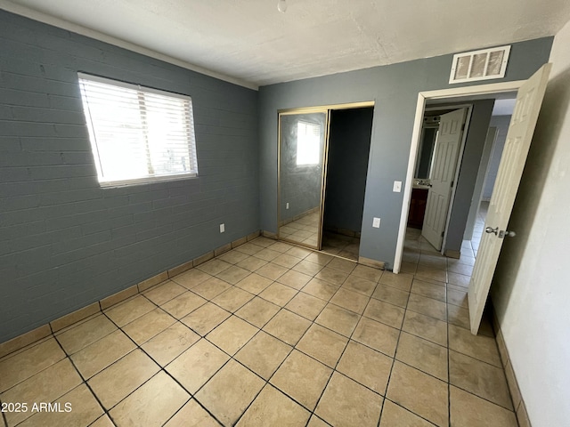 unfurnished bedroom featuring a closet, light tile patterned flooring, visible vents, and baseboards