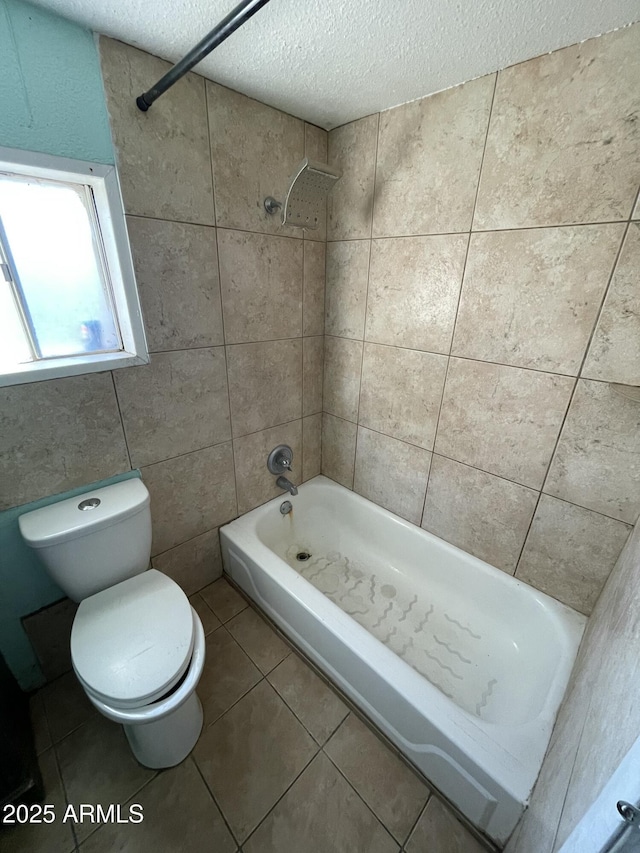 bathroom featuring shower / bath combination, toilet, tile patterned floors, a textured ceiling, and tile walls