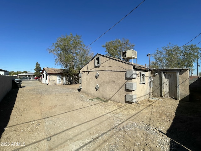 view of property exterior featuring driveway, central AC unit, fence, and stucco siding