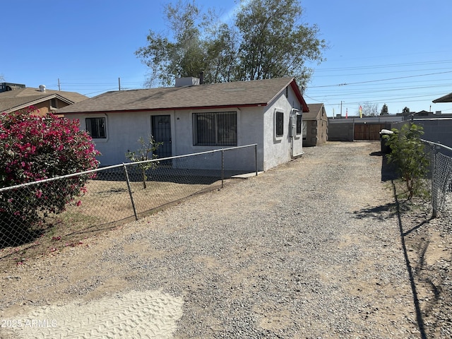 view of front of home with fence private yard, roof with shingles, and stucco siding