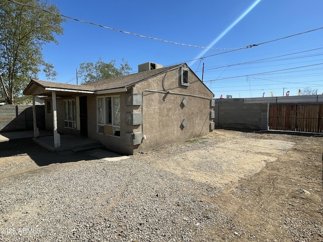 view of side of property with central air condition unit, fence, and stucco siding