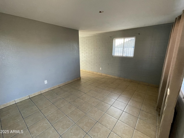 spare room with brick wall and light tile patterned floors