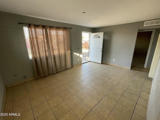 empty room featuring a healthy amount of sunlight, visible vents, baseboards, and light tile patterned floors