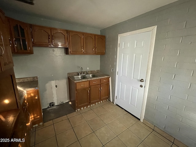 kitchen with light tile patterned floors, light countertops, brown cabinetry, and a sink