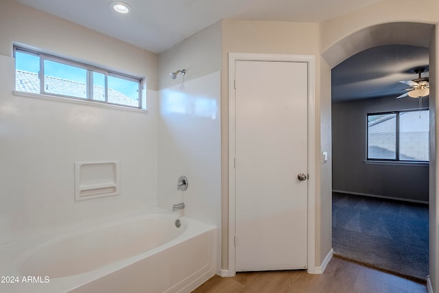 bathroom with shower / tub combination, ceiling fan, hardwood / wood-style floors, and a healthy amount of sunlight