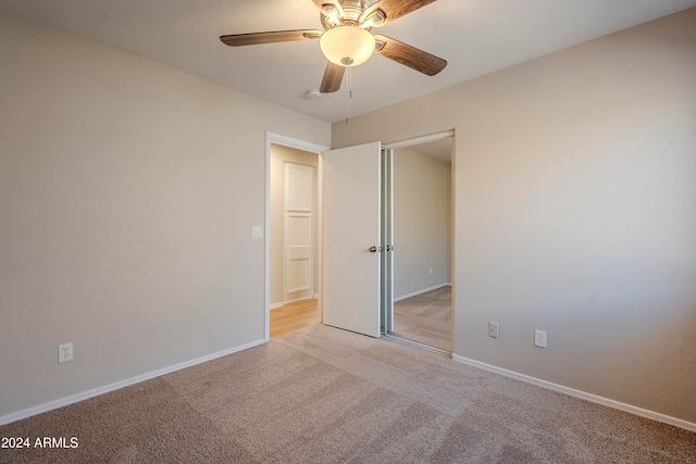 unfurnished bedroom featuring a closet, light colored carpet, and ceiling fan