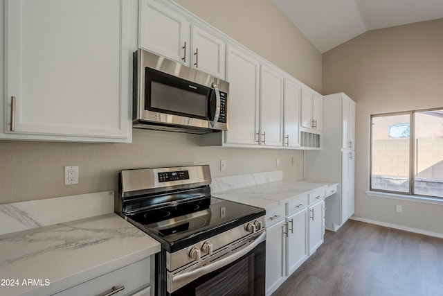 kitchen with white cabinetry, light stone countertops, lofted ceiling, and appliances with stainless steel finishes