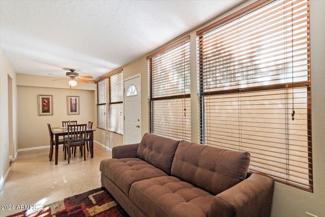 living room featuring light tile patterned flooring, ceiling fan, and a textured ceiling