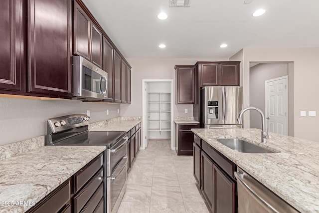 kitchen with light stone countertops, stainless steel appliances, recessed lighting, and a sink