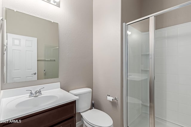 bathroom featuring toilet, vanity, and a shower stall