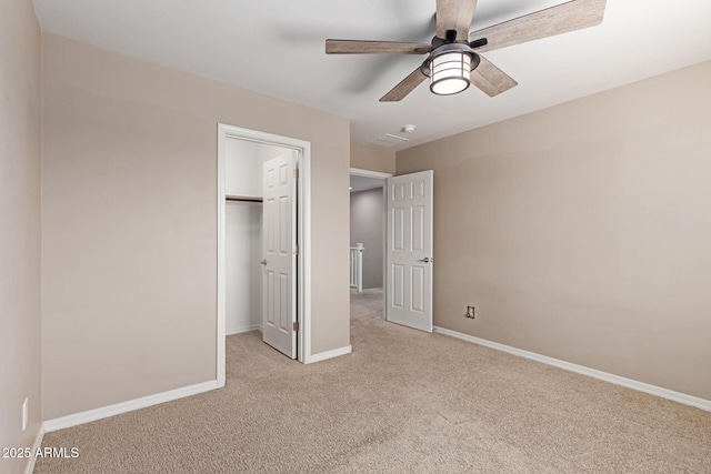 unfurnished bedroom with a closet, a ceiling fan, a walk in closet, baseboards, and carpet floors