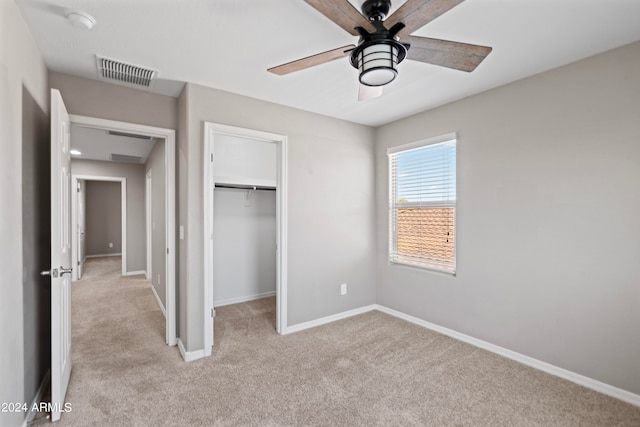 unfurnished bedroom with a spacious closet, light carpet, ceiling fan, and a closet