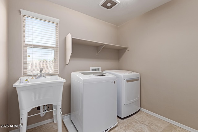 laundry room with baseboards, separate washer and dryer, laundry area, and a sink