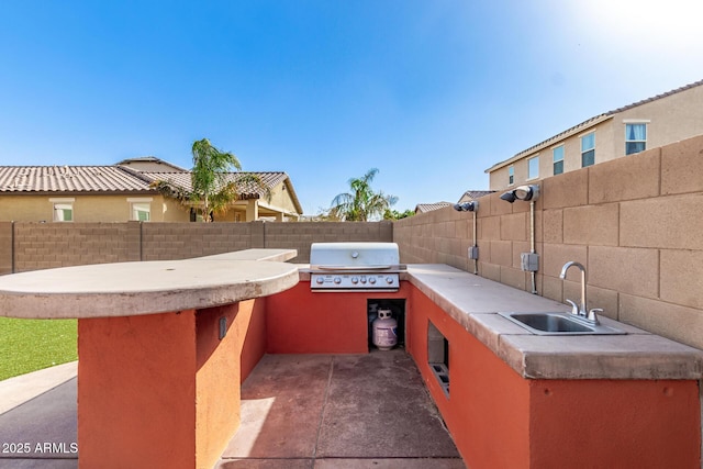 view of patio / terrace featuring exterior kitchen, a sink, a grill, and a fenced backyard