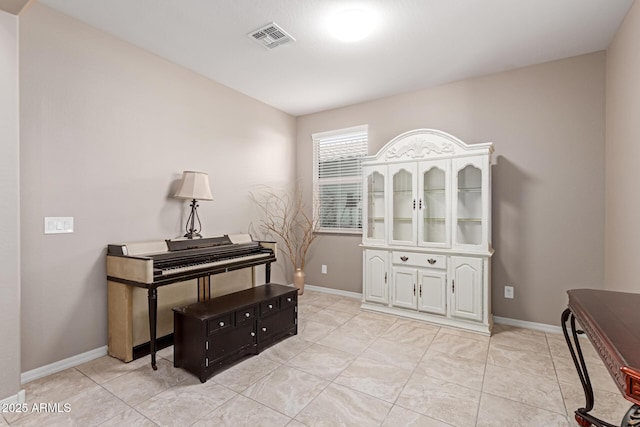 living area with baseboards, visible vents, and light tile patterned flooring