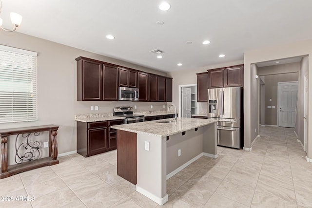 kitchen featuring light stone countertops, a sink, dark brown cabinetry, visible vents, and appliances with stainless steel finishes