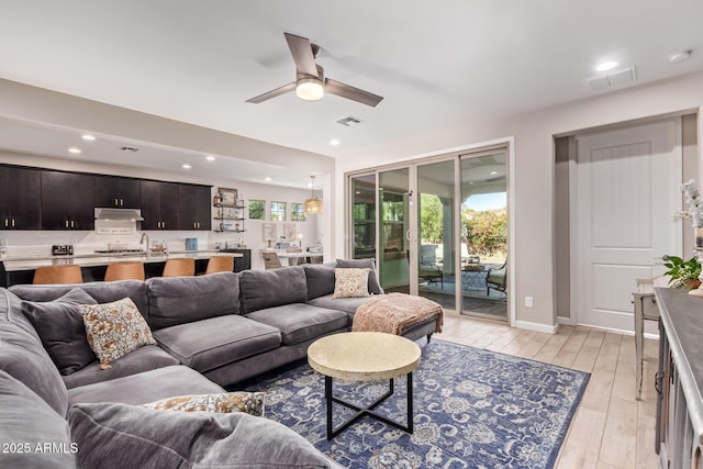 living room with light hardwood / wood-style flooring and ceiling fan