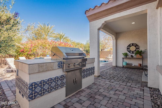 view of patio featuring a grill, a fenced in pool, and exterior kitchen