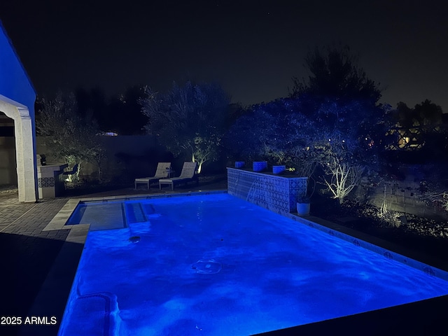 pool at night with a patio area