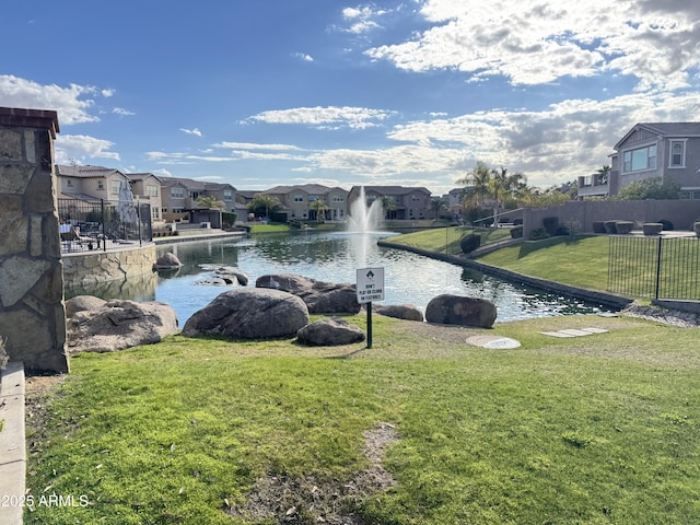 view of property's community with a water view and a lawn