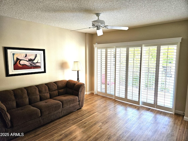 living room with ceiling fan, a textured ceiling, and light hardwood / wood-style flooring