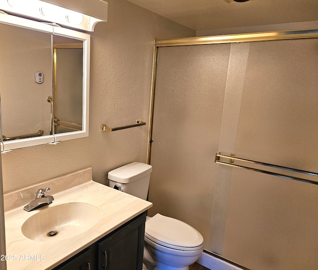 bathroom with a shower with shower door, toilet, and vanity