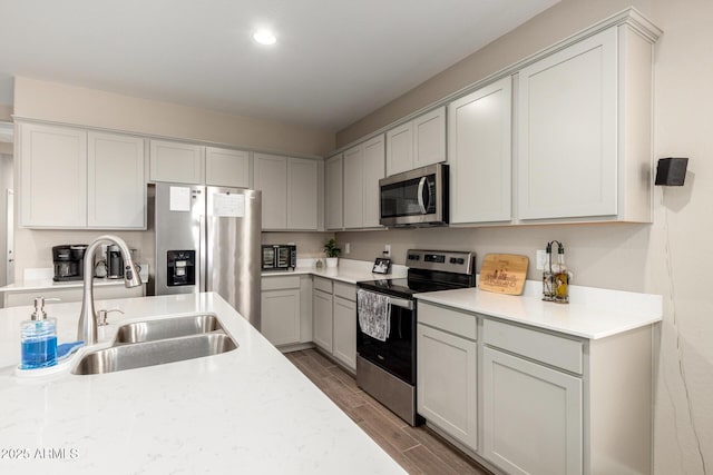 kitchen with light countertops, appliances with stainless steel finishes, a sink, and light wood-style flooring
