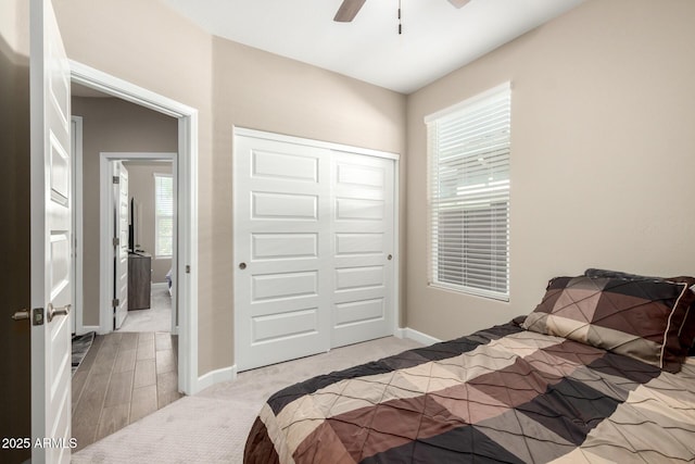 bedroom featuring a closet, baseboards, ceiling fan, and light carpet