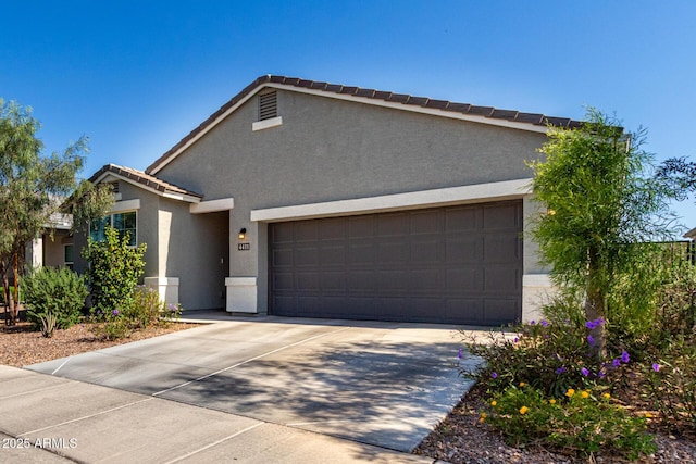 ranch-style house featuring a garage, stucco siding, a tiled roof, and concrete driveway