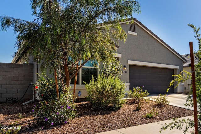 view of front of home featuring a garage, fence, driveway, and stucco siding