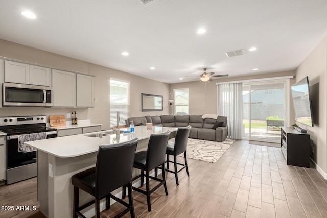 kitchen with visible vents, a sink, light countertops, light wood-style floors, and stainless steel appliances