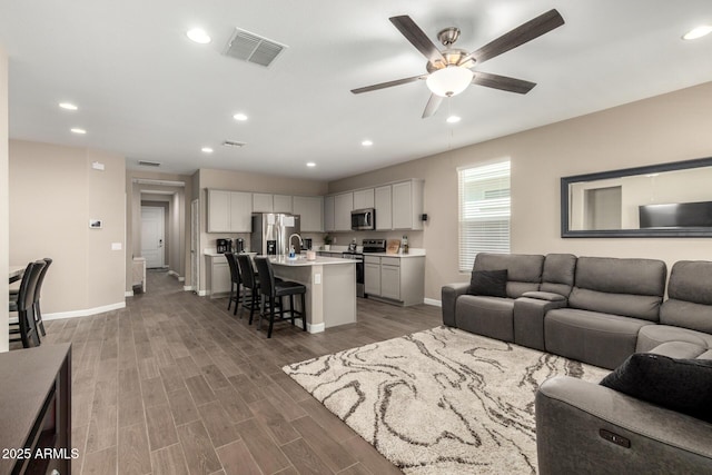 living area featuring a ceiling fan, baseboards, recessed lighting, wood finished floors, and visible vents