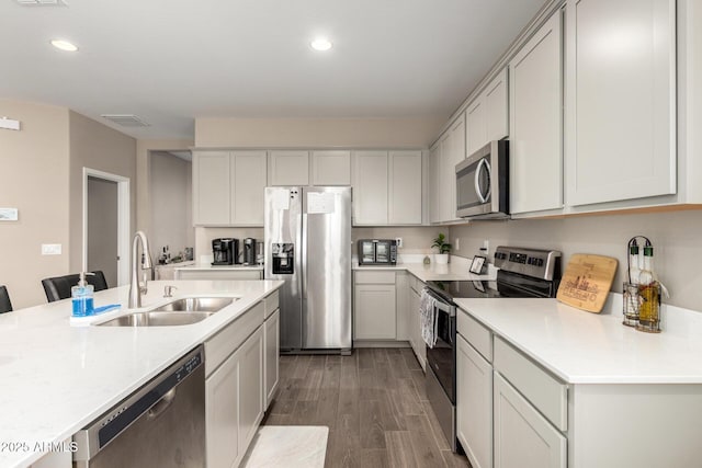 kitchen with a sink, light countertops, stainless steel appliances, recessed lighting, and wood finished floors