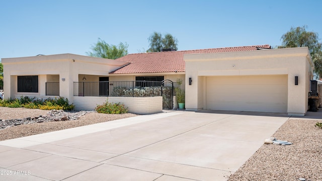 view of front of house featuring concrete driveway, a fenced front yard, a tile roof, an attached garage, and stucco siding