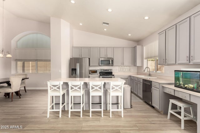 kitchen featuring stainless steel appliances, a kitchen island, a breakfast bar, and sink