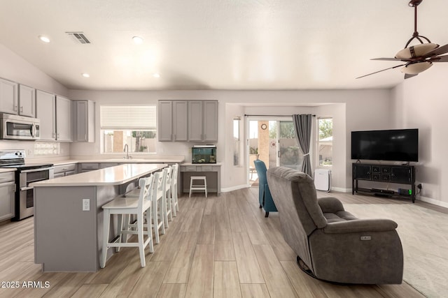 kitchen with sink, a breakfast bar, stainless steel appliances, a center island, and light wood-type flooring